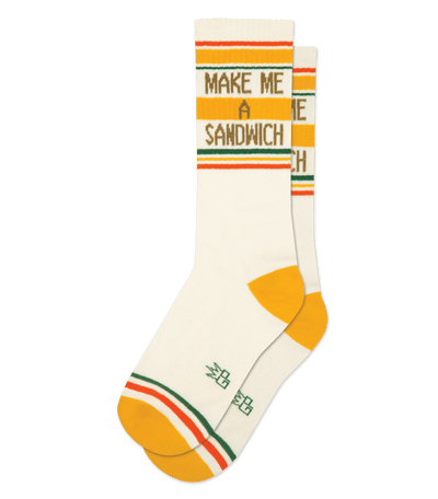 Natural cotton socks with brass accents, text "MAKE ME A SANDWICH", orange and green stripes, no background.