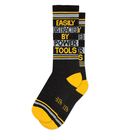 Black and gold socks with text: "Easily Distracted By Power Tools." Gold accents on toes and heels.