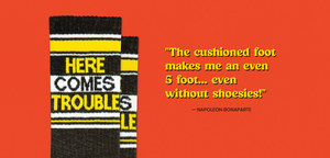 Banner with sock that says "HERE COMES TROUBLE" next to quote that says "THE CUSHIONED FOOT MAKES ME AN EVEN 5 FOOT... EVEN WITHOUT SHOESIES. - NAPOLEON BONAPARTE"