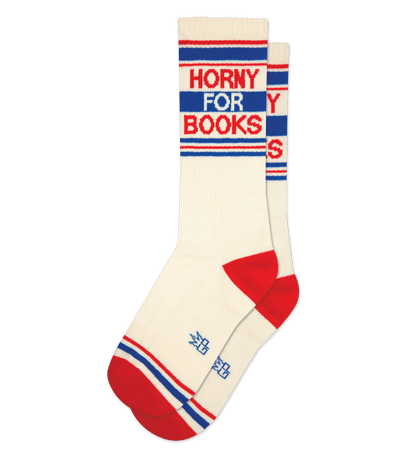 A pair of cream-colored socks with red toes and text "HORNY FOR BOOKS" on the ankle.