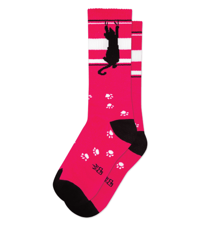 "Hot pink sock with white stripes, black cat silhouette, and paw prints, no background color."